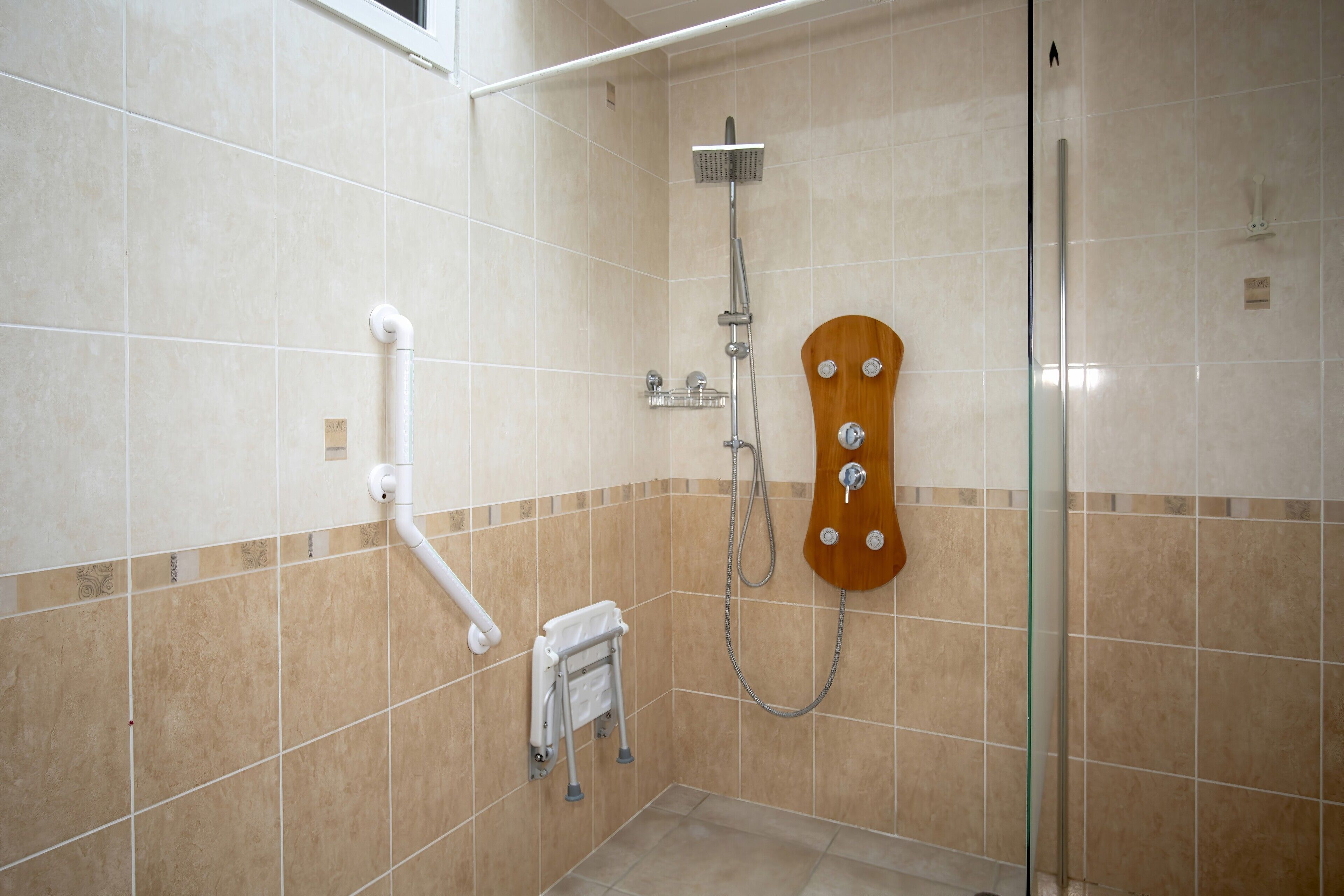 Ducha con cabezal de ducha manual, cerramiento de vidrio y panel de madera.