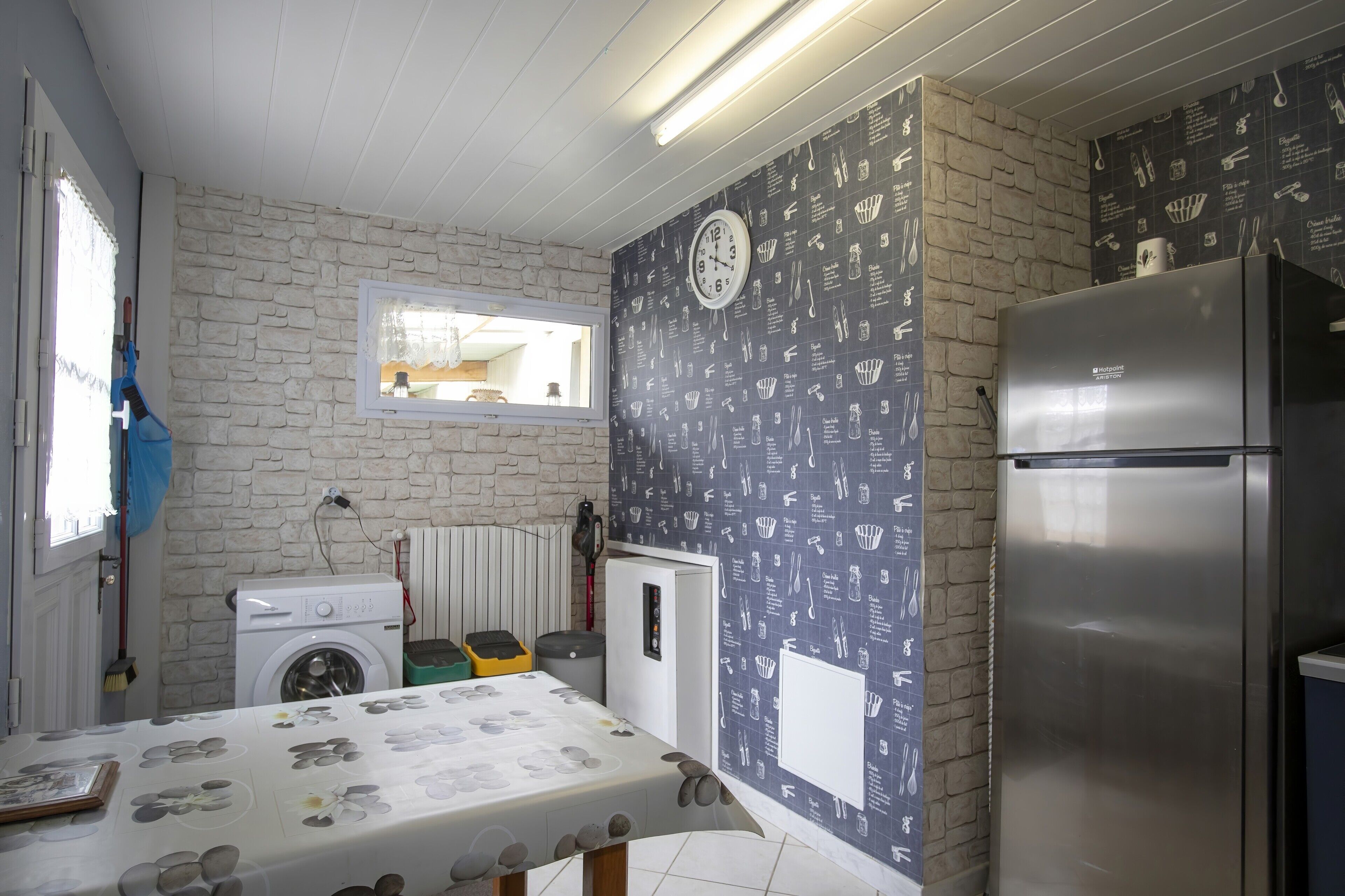 Une cuisine équipée d’un lave-linge, d’un réfrigérateur, d’une fenêtre avec vue et d’une horloge murale.
