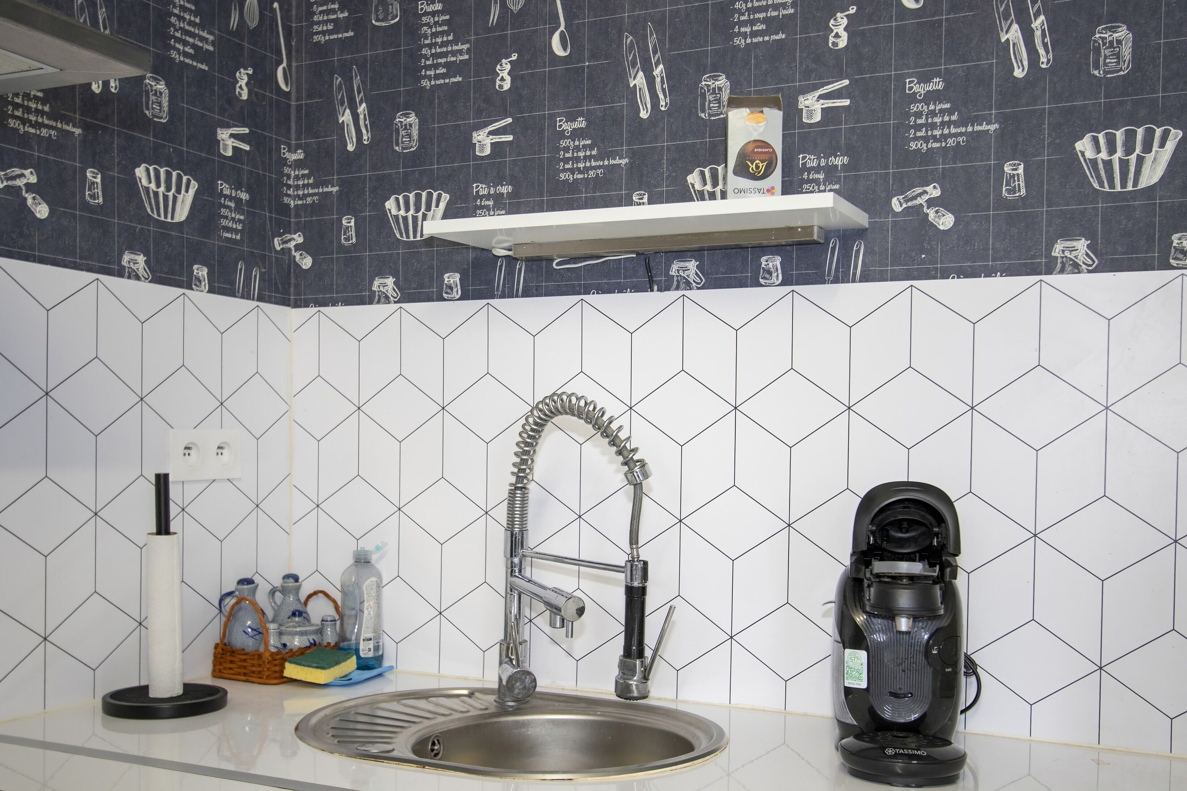 A kitchen with a modern faucet, a coffee machine, and a shelf with kitchen utensils.