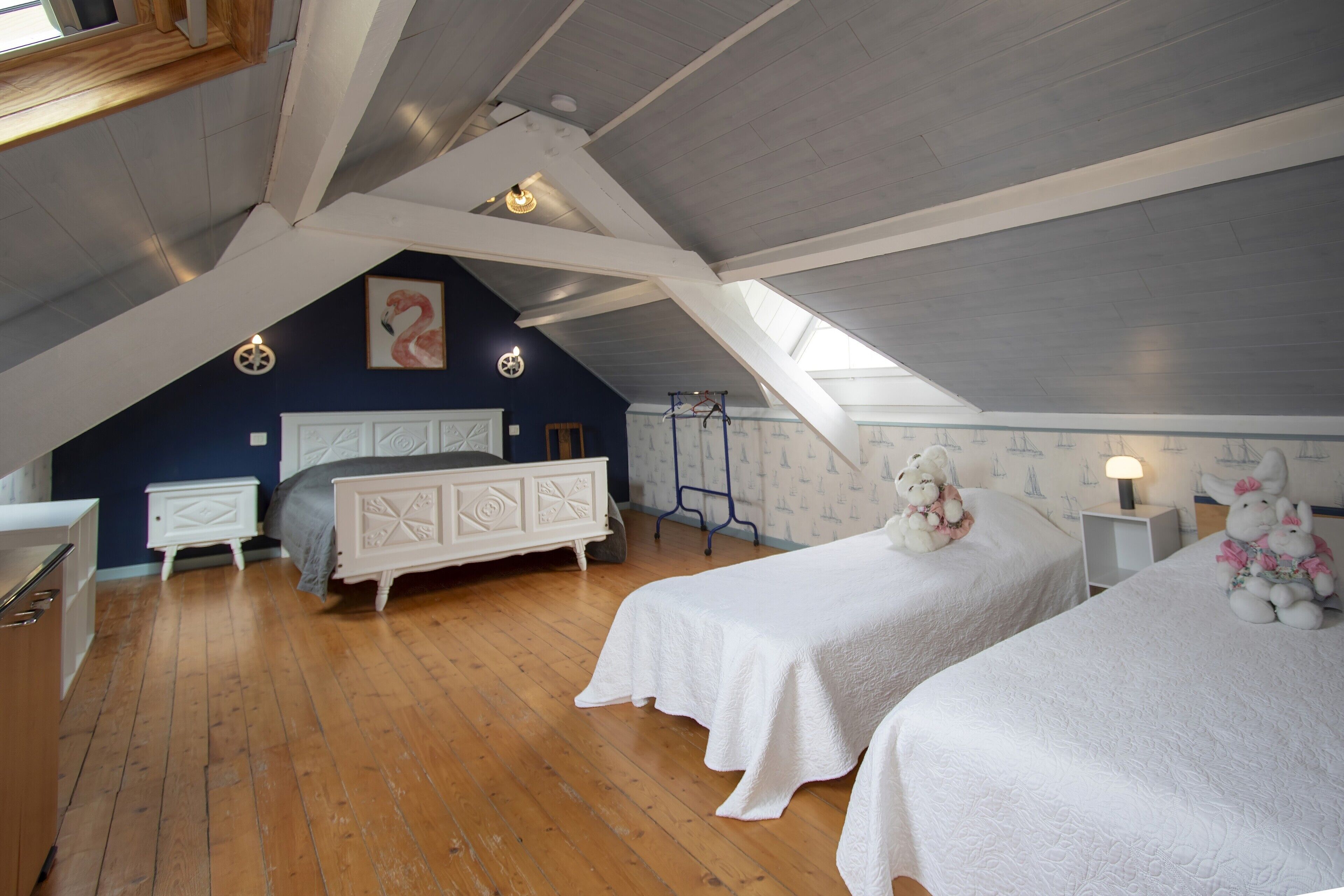 Ein Schlafzimmer mit zwei Betten, Holzboden, schrägem Dach und einem Oberlicht.