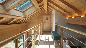 Un interior de madera con techo inclinado, un banco y una puerta con un símbolo de árbol.