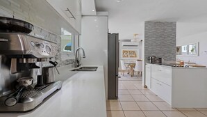 Uma cozinha moderna com máquina de café expresso embutida, pia e área de jantar com mesa e cadeiras.