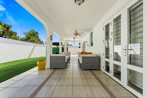 A covered patio with outdoor furniture, a ceiling fan, and sliding glass doors. - Casa Palma Serena - Garden Retreat • Tropical Stay (Santa Isabel)