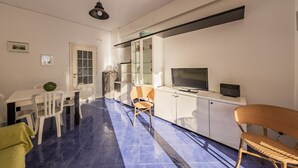 Un espacio habitable compacto con comedor, televisor y kitchenette.