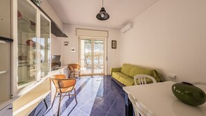 Una habitación con una mesa de comedor, un sofá, una silla, un televisor y un amplio ventanal con vistas al exterior.