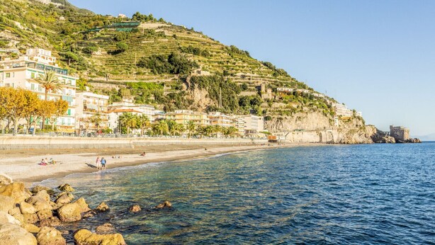 Un pueblo costero con casas escalonadas, una playa y afloramientos rocosos.