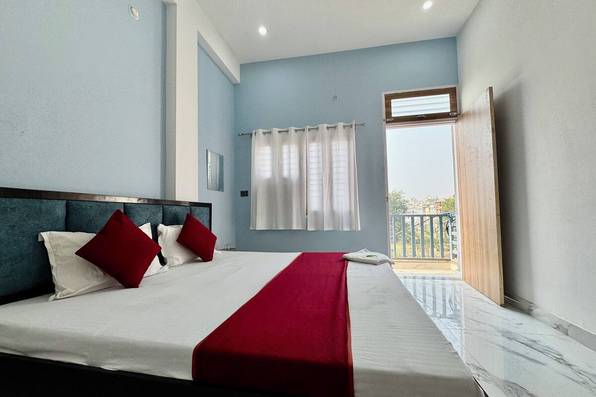 A hotel room with a bed, a balcony, and a view of buildings.