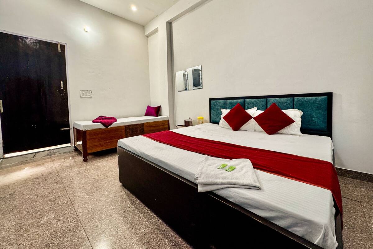 A modern hotel room with a large bed, a bedside table, a wardrobe, and a bathroom.