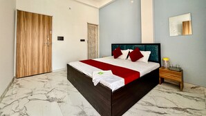 A modern hotel room with a large bed, marble flooring, a wooden door, and a small bedside table with a lamp. - Hotel radha Aradhya Sadan (Mathura)