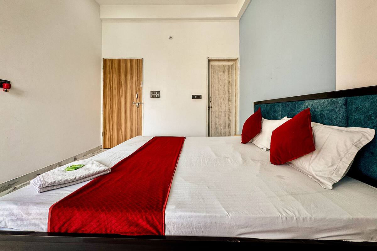 A hotel room with a large bed, a wooden door, and a blue accent wall.