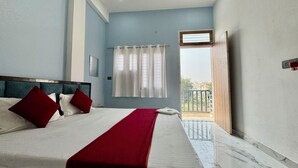 A hotel room with a bed, a window with curtains, a balcony, and a view of the outside. - Hotel radha Aradhya Sadan (Mathura)