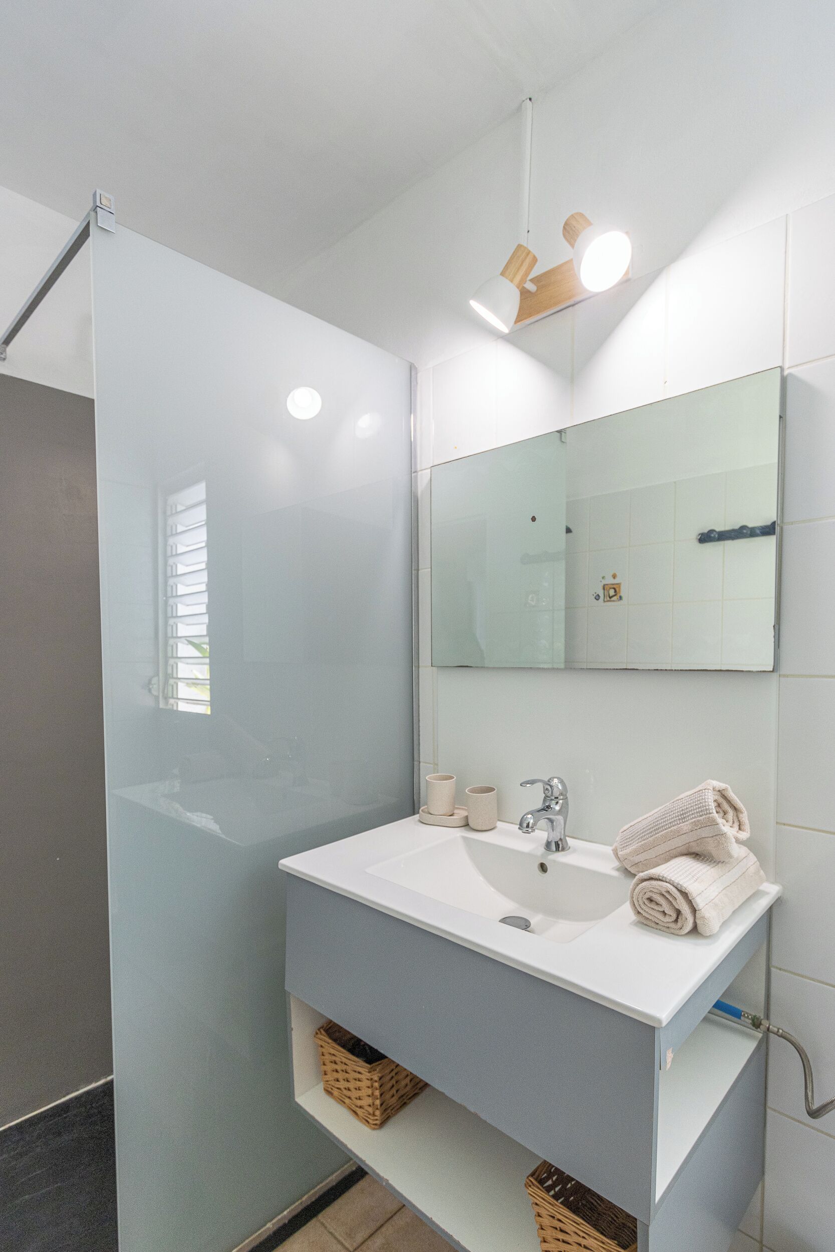A modern bathroom with a glass shower enclosure, a white sink, and a large mirror.