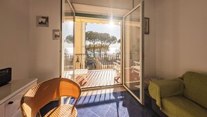 A room with a sliding glass door leading to an outdoor deck with a view of trees and a body of water. - Casa D'Amato - Maiori (Maiori)