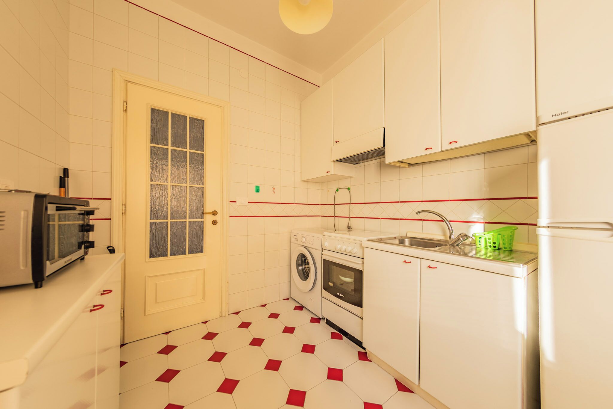 A compact kitchen with a washing machine, a sink, and a refrigerator.