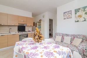 Une cuisine moderne avec des meubles en bois, une table à manger recouverte d’une nappe à motifs floraux et un canapé à motifs floraux.
