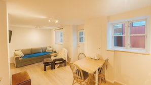 A compact living space with a sofa, a dining table, and a small kitchen area. - Cosy First Floor Apt near Harbour & Cafes (Hafnarfjörður)