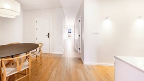 A modern, well-lit hallway with a dining area featuring a wooden table and chairs. - Recently refurbished 3 bedroom apartment with terrace (Barcelona)