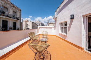 A rooftop terrace with wicker furniture and a view of surrounding buildings. - Recently refurbished 3 bedroom apartment with terrace (Barcelona)