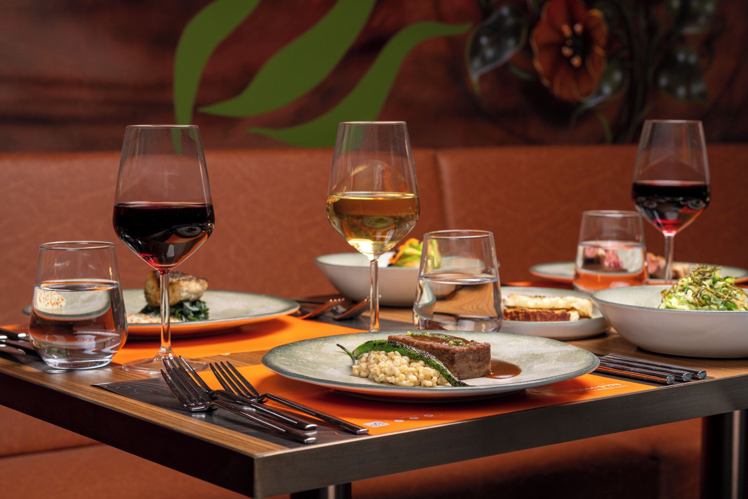 A dining table set with plates of food, glasses of wine, and cutlery.