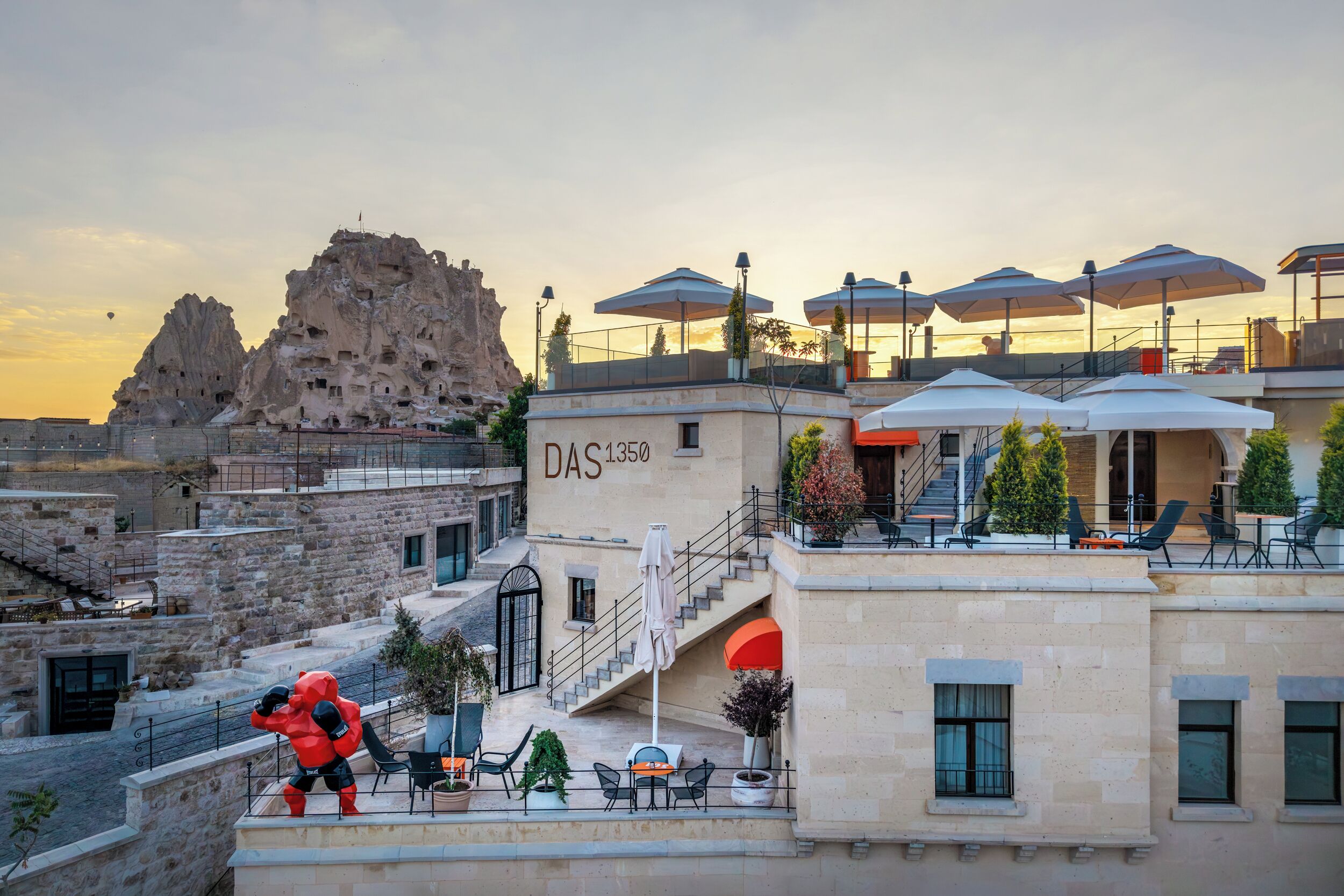 Un hotel con terraza exterior, vistas a formaciones rocosas y una escalera que lleva a la entrada.
