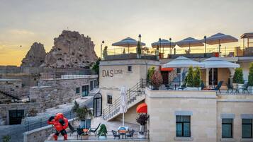 Un hotel con terraza exterior, vistas a formaciones rocosas y una escalera que lleva a la entrada.