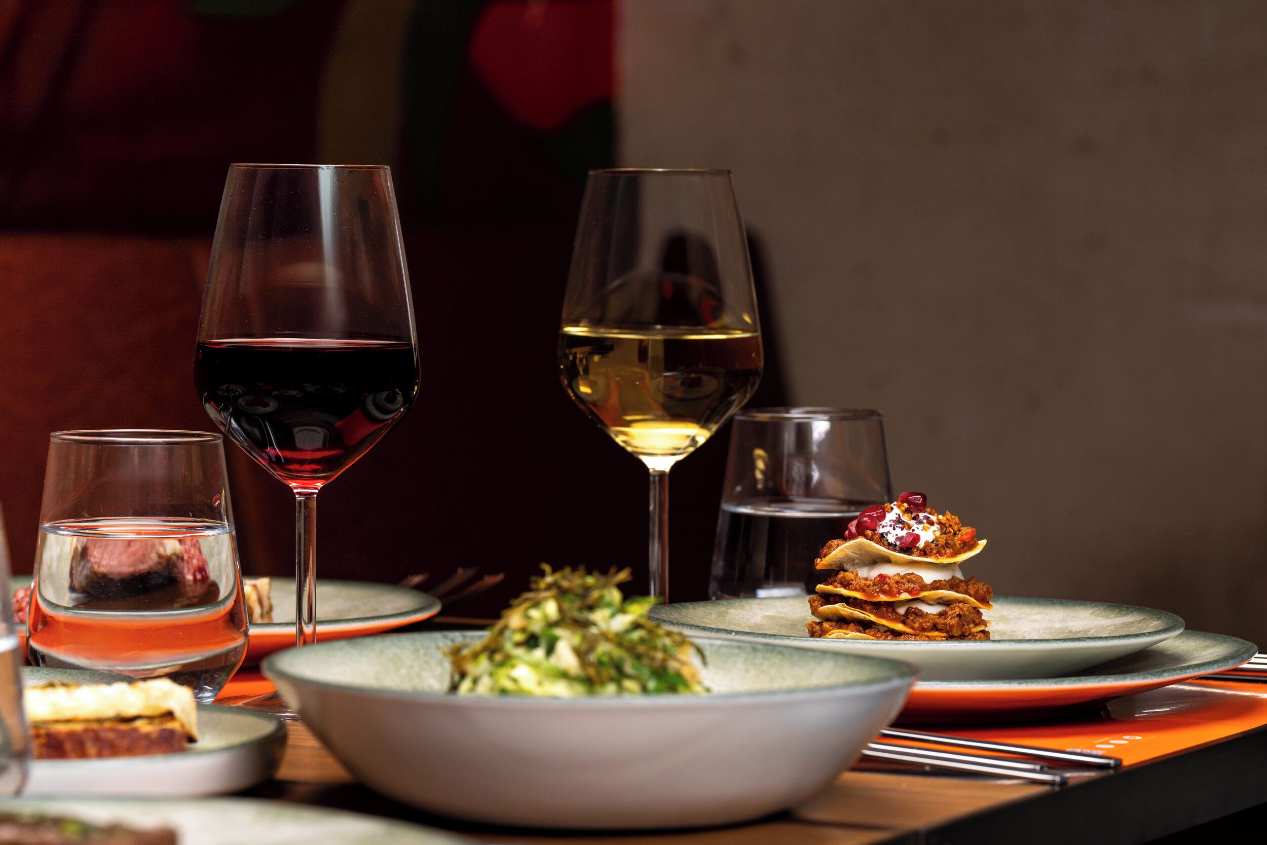 Una mesa de comedor con diversos platos y copas de vino.
