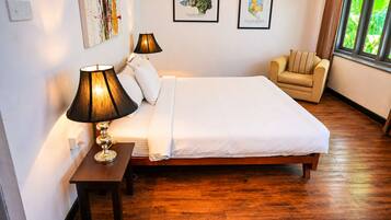 A bedroom with a wooden bed, two bedside lamps, a chair, and framed artwork on the wall.