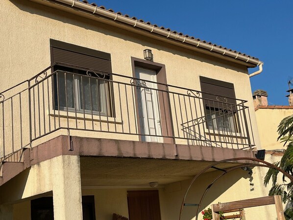 A two-story building with a balcony, a door, and a window.