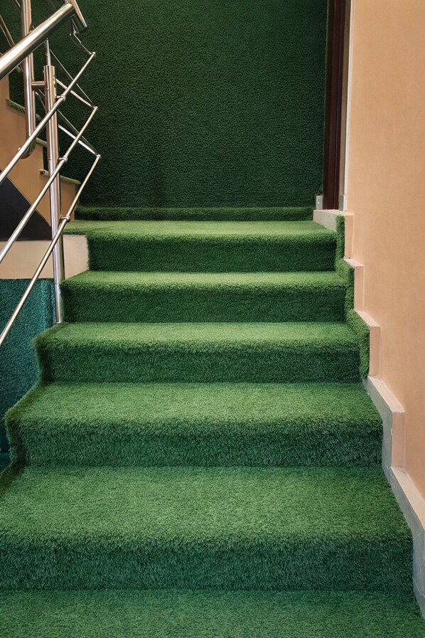 A staircase with green carpeted steps and a metal railing.