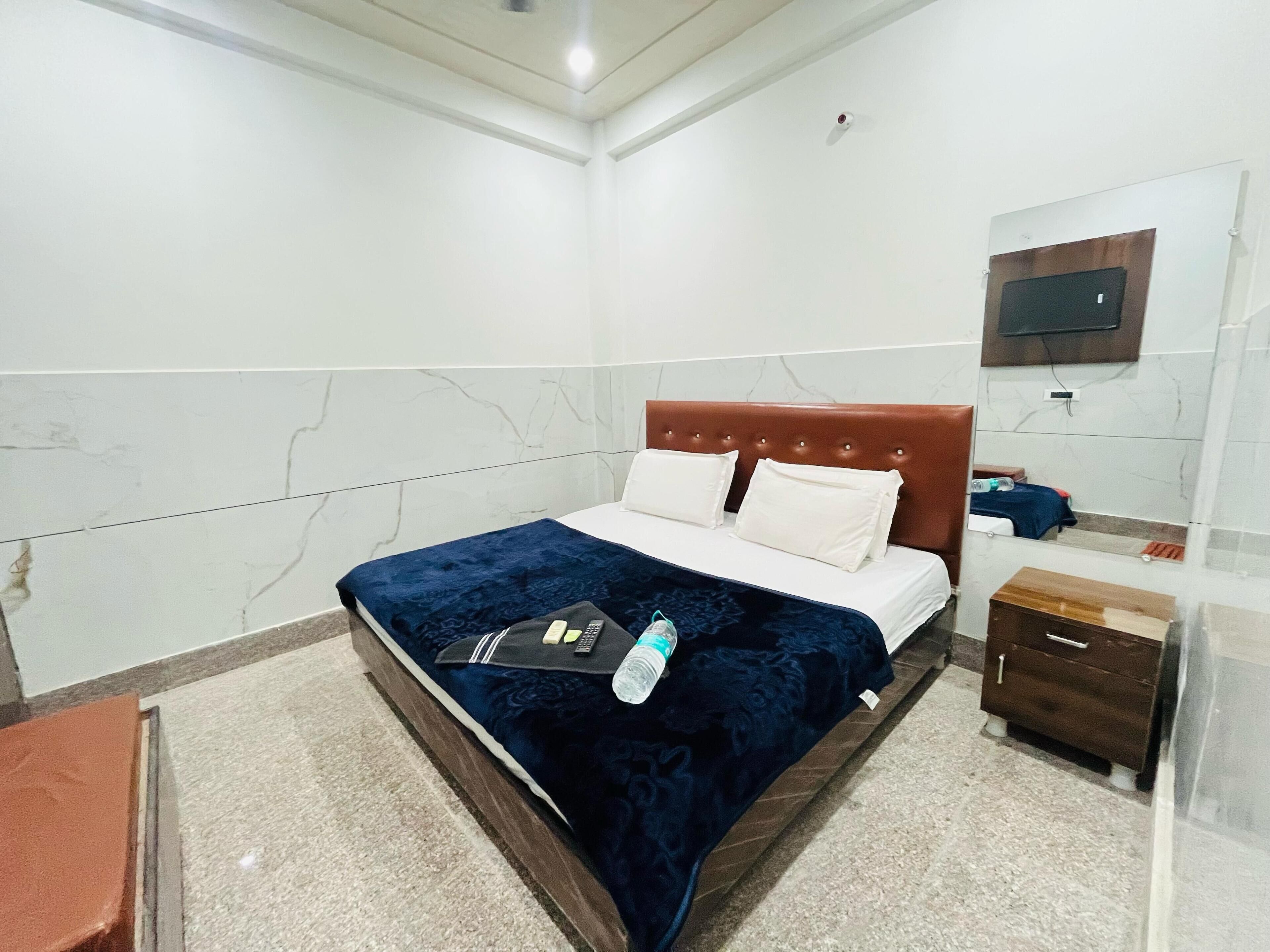 A hotel room with a bed, a nightstand, a mirror, and a TV mounted on the wall.