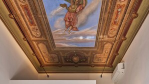 A hotel room with a bed, a desk, a chair, a mirror, and a ceiling mural. - Fantini Rooms- Fori Imperiali (Rome)