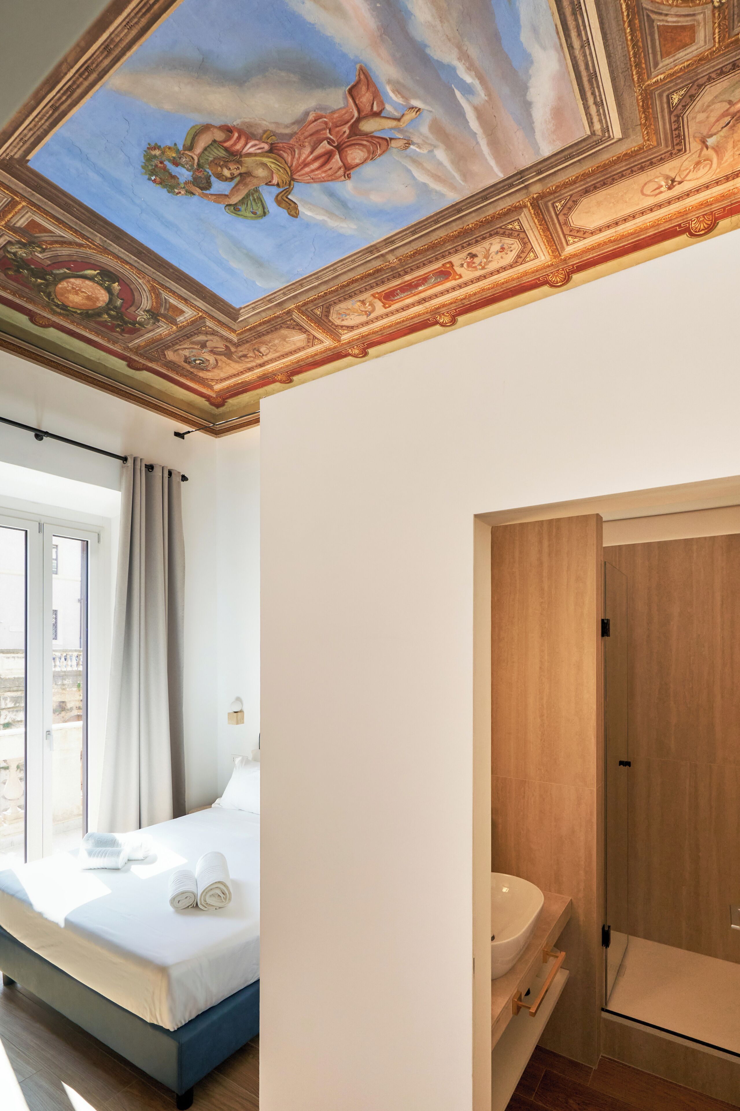 Una habitación con cama, baño y un mural en el techo.