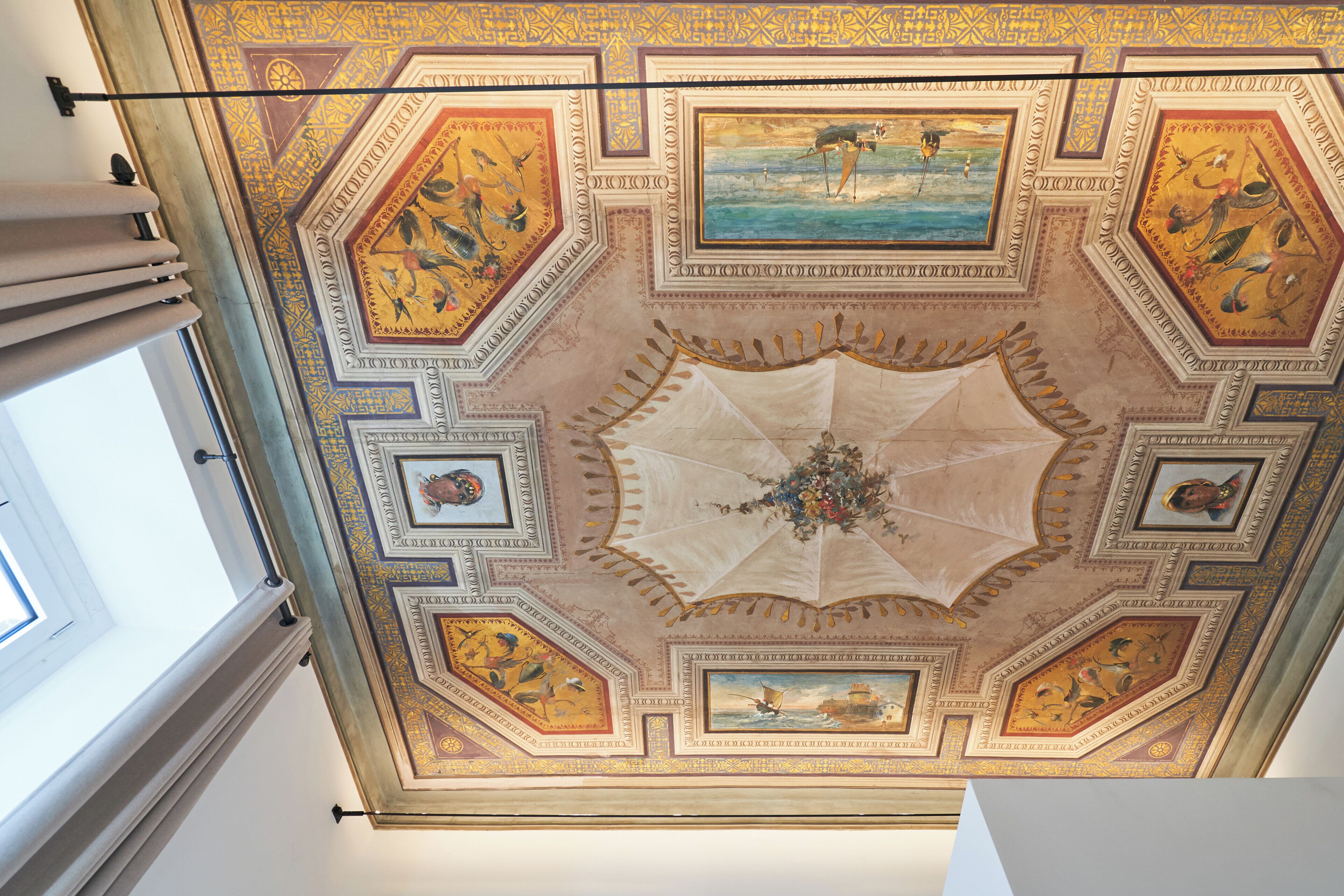 A ceiling with intricate geometric patterns and framed artwork.