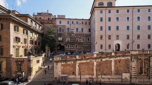 A historic building with a central staircase, multiple windows, and a brick wall. - Fantini Rooms- Fori Imperiali (Rome)