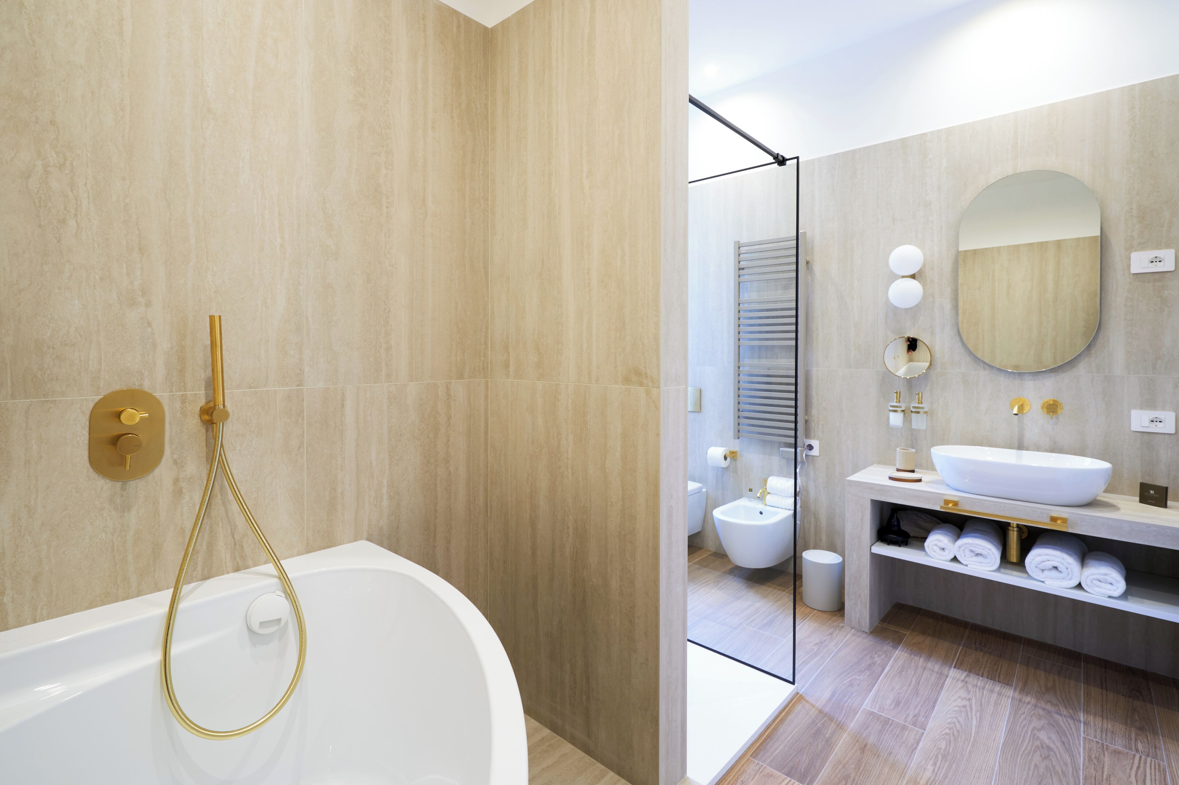 A modern bathroom with a bathtub, a sink, a mirror, and a toilet.
