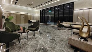 Een moderne lobby met zitgedeeltes, een receptiebalie en een groot raam.