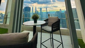 Een balkon met een glazen deur, een ronde tafel met een plant in pot, en twee stoelen.