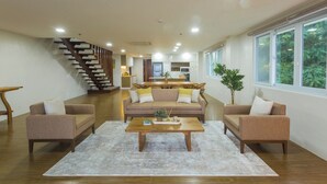 A spacious living area with a sofa set, a coffee table, and a staircase leading to a kitchen. - Vine and Canopy (Morong)