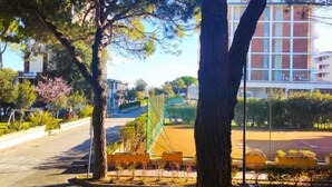A tree-lined street with a building in the background. - Central Apartment With Terrace (San Michele al Tagliamento)