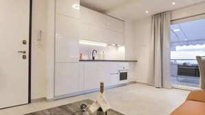 Una cocina moderna con armarios blancos, horno empotrado y un amplio ventanal con vistas al cielo.