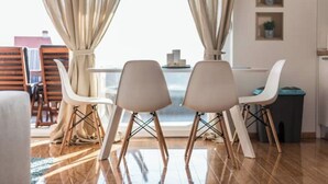 Un espace repas moderne comprenant une table et quatre chaises, une fenêtre avec des rideaux et une vue sur l’extérieur.