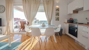 Une cuisine moderne avec des armoires blanches, un four encastré et un coin repas comprenant une table et des chaises.