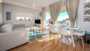 Un salon moderne comprenant un canapé, une table basse, un téléviseur et un coin repas avec des chaises et une table.