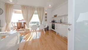 Une cuisine moderne avec des meubles blancs et un coin repas comprenant une table et des chaises en verre.