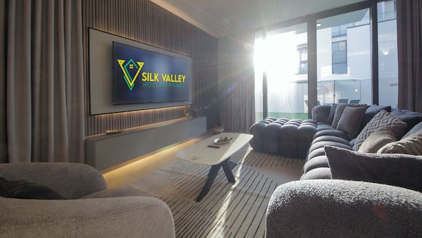 Een moderne woonkamer met een flatscreen-tv, comfortabele zitplaatsen en een groot raam met uitzicht.