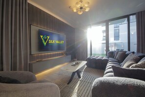 En moderne stue med et fladskærms-tv, behagelige siddepladser og et stort vindue med udsigt.