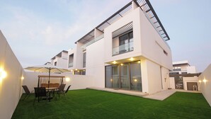 Een modern huis met twee verdiepingen, een plat dak, grote ramen en een verzorgd gazon.