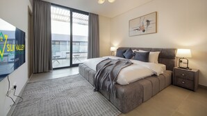 Een moderne hotelkamer met een groot bed, een flatscreen televisie, een plafondventilator en uitzicht op de stad door het raam.
