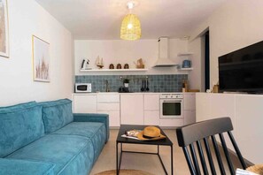 A compact living space with a kitchenette, a sofa, a dining table, and a television. - La Perle Bleue - Air-conditioned 1-bed flat for 4, near Cap d'Agde (Agde)