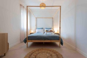 Un dormitorio con una cama con dosel, lámparas de noche y una alfombra decorativa.